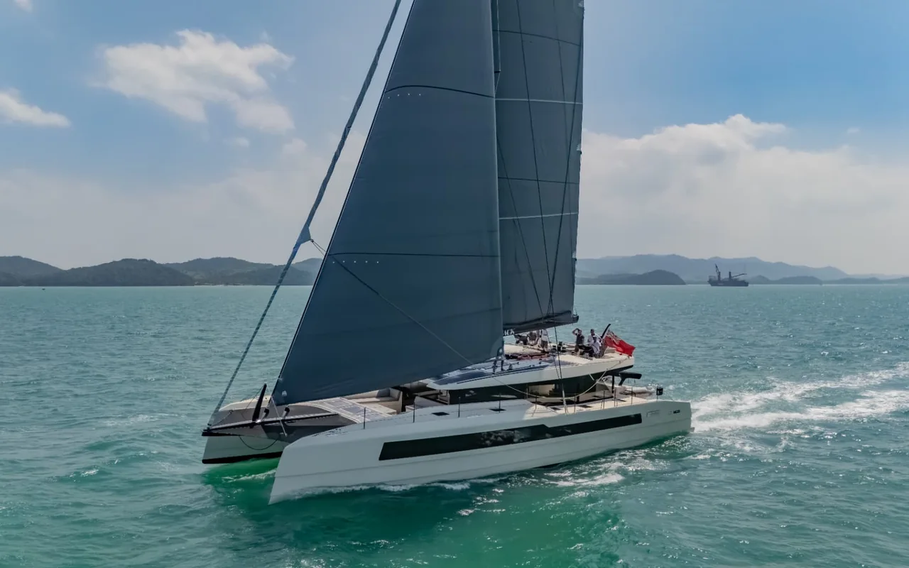 Owners sailing a Cure catamaran under full sail in coastal waters