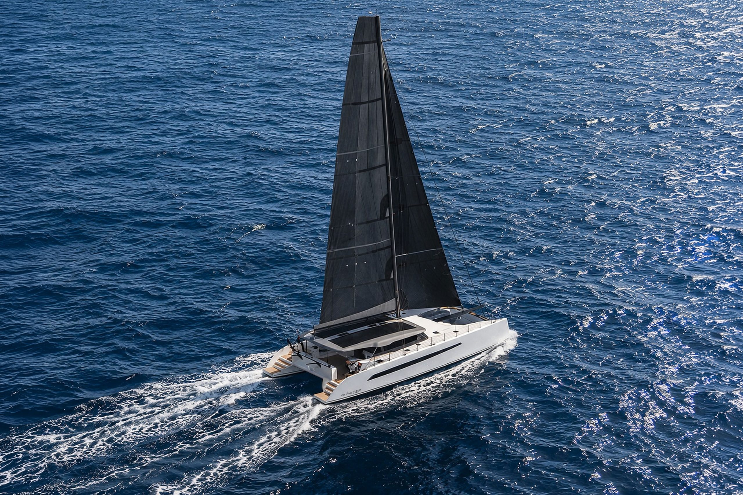 Cure catamaran sailing offshore at sunset