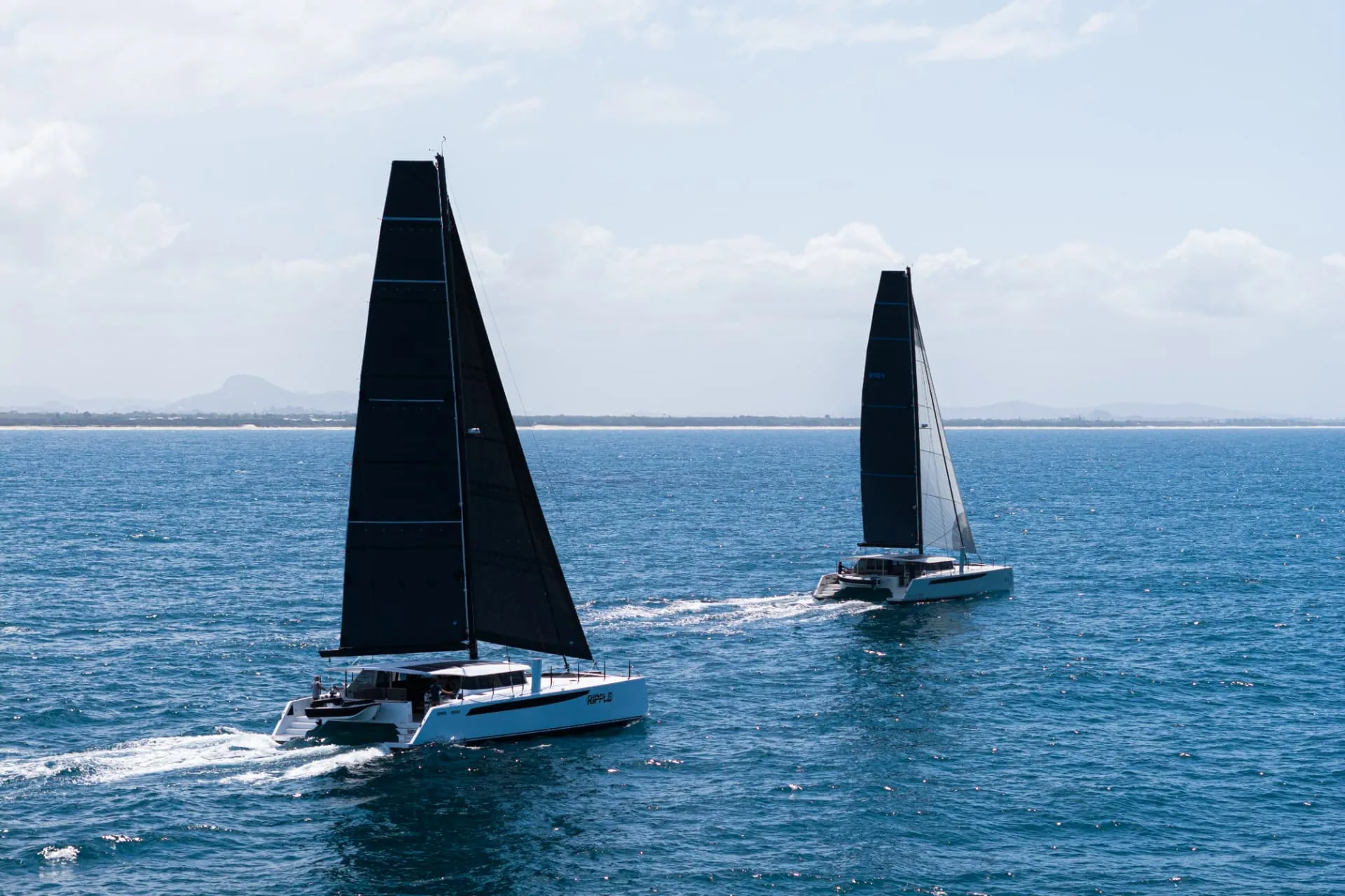Two Cure catamarans sailing on open blue water